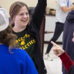 A teacher in a group holds her arm up to celebrate.
